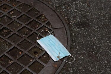 Discarded blue medical mask laying on ground