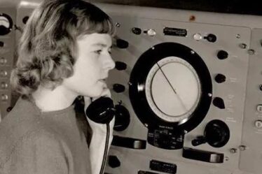 woman sits with phone in hand at radar console