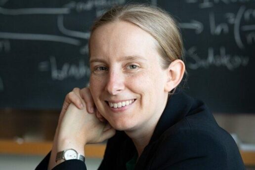 Tracy Slatyer poses in front of blackboard covered in physics equations