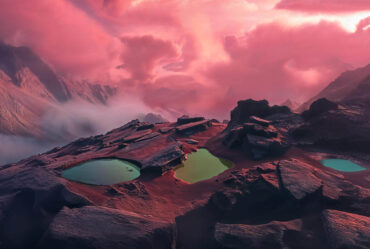 The mountainous landscape of an imaginary planet with pink clouds hovering above